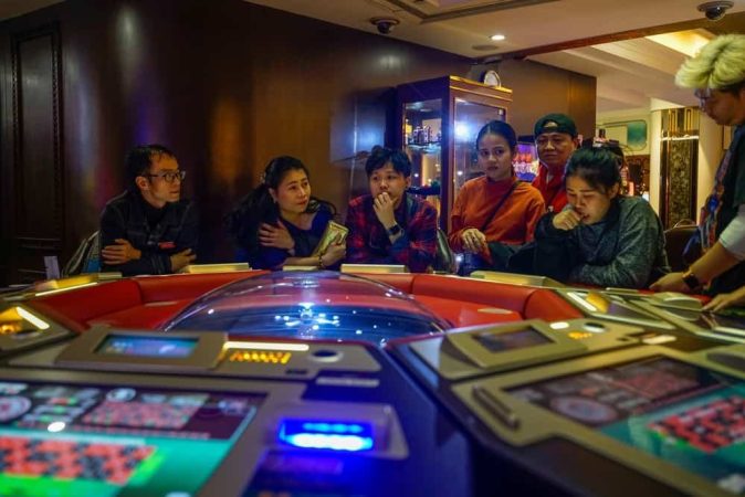 People sitting around a table of casino games during casino junkets trips